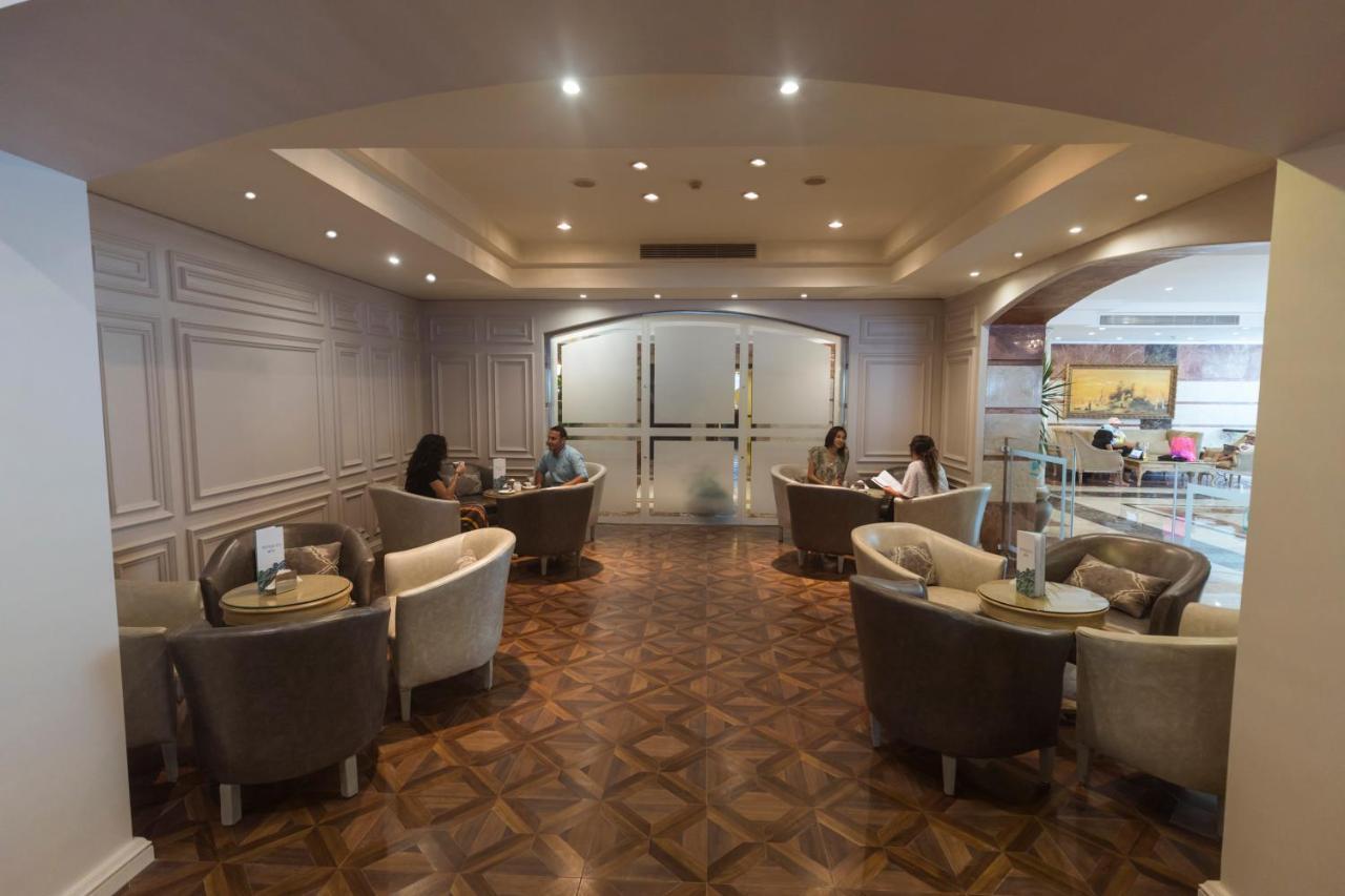 Sunrise Alex Avenue Hotel Alexandria Exterior foto The photo shows a well-lit lounge area with a modern and elegant design. There are several comfortable seating arrangements, including plush chairs and small tables. The flooring appears to be made of a decorative wood pattern. In the background, the