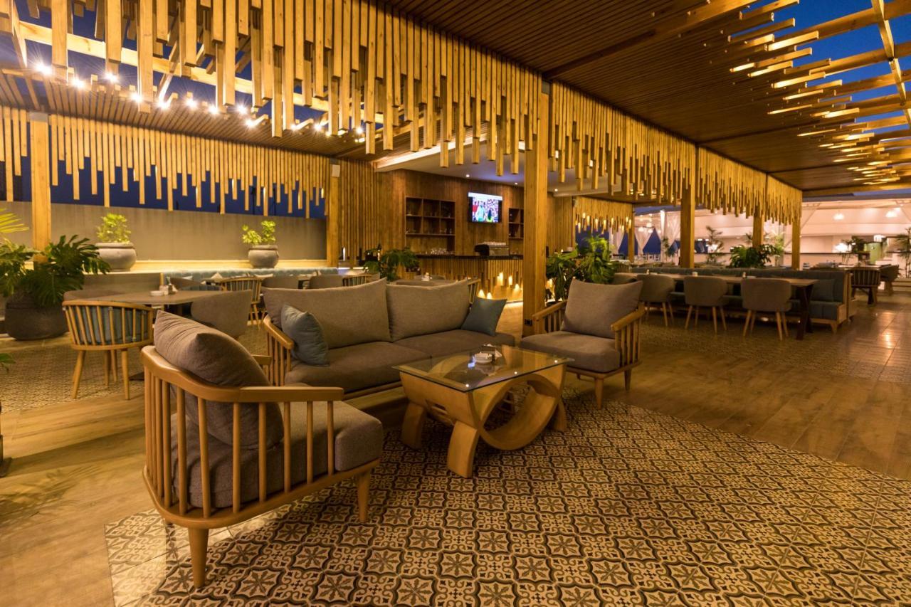 Sunrise Alex Avenue Hotel Alexandria Exterior foto The photo depicts a stylish and modern lounge or restaurant interior. It features wooden furniture, including a sofa and armchairs, arranged around a central coffee table. The space is characterized by warm lighting and decorative elements, such as h