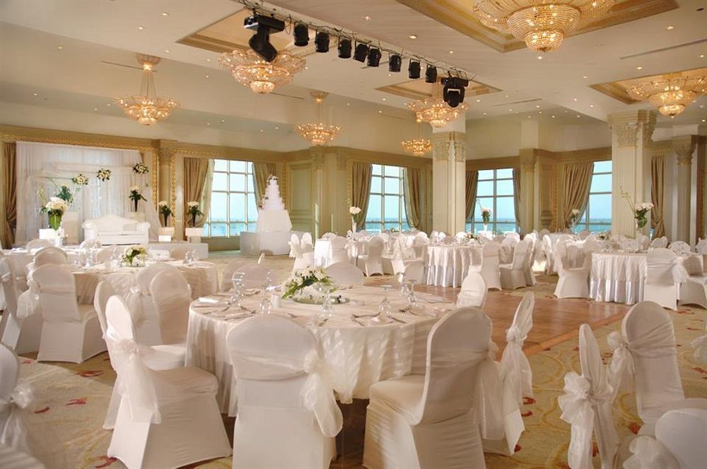 Sunrise Alex Avenue Hotel Alexandria Exterior foto The photo depicts an elegant banquet hall set up for a formal event, likely a wedding or reception. The room features several round tables covered with white tablecloths and adorned with floral centerpieces. Chairs are also dressed in white covers, c