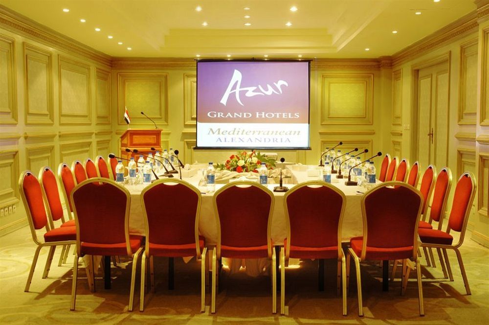 Sunrise Alex Avenue Hotel Alexandria Exterior foto The photo shows a conference room set up for a meeting or event. There is a large oval table surrounded by red chairs, and the table is equipped with microphones and bottles of water. In the background, there is a projector screen displaying the logo