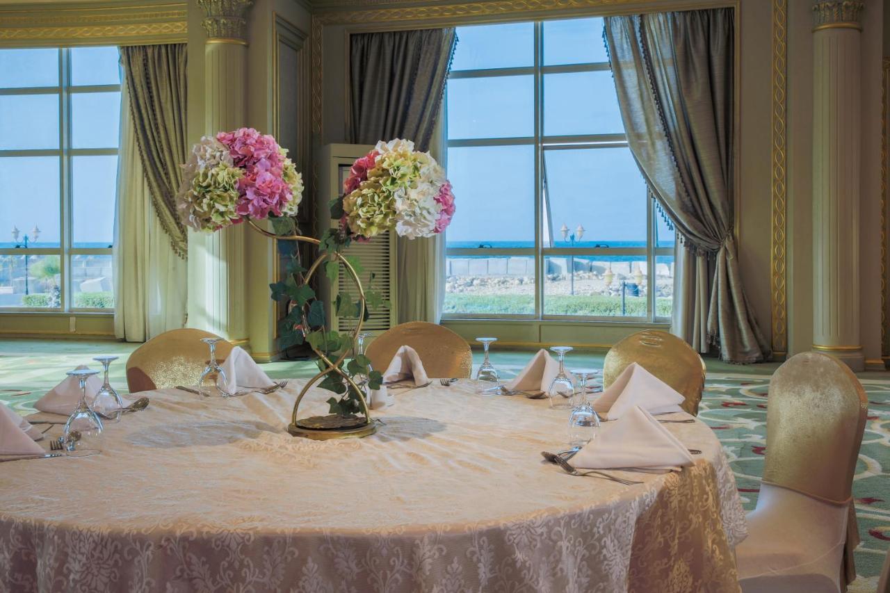 Sunrise Alex Avenue Hotel Alexandria Exterior foto The photo depicts a beautifully arranged round dining table set in an elegant room. The table is covered with a light-colored lace tablecloth and features an artistic floral centerpiece with pink and white flowers. The place settings include folded n